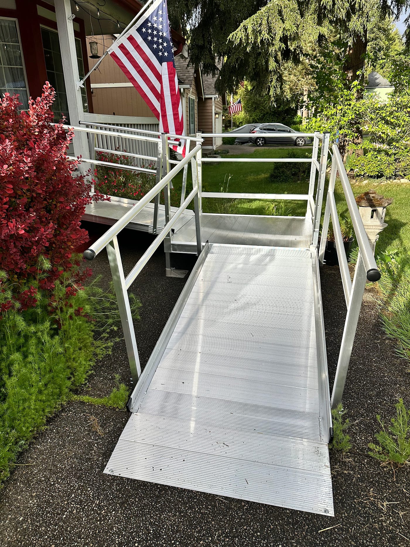 Front porch entry with flag, welcome mat, and seating.